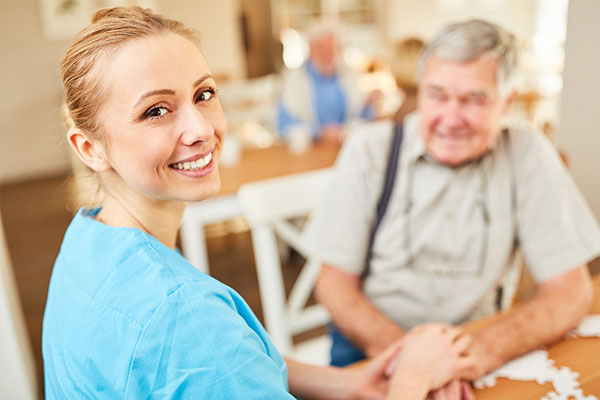 Senioren- & Pflegeheime - Berufsbekleidung. Hier im Bild: Eine Pflegekraft bei der Bewohnerbetreuung.